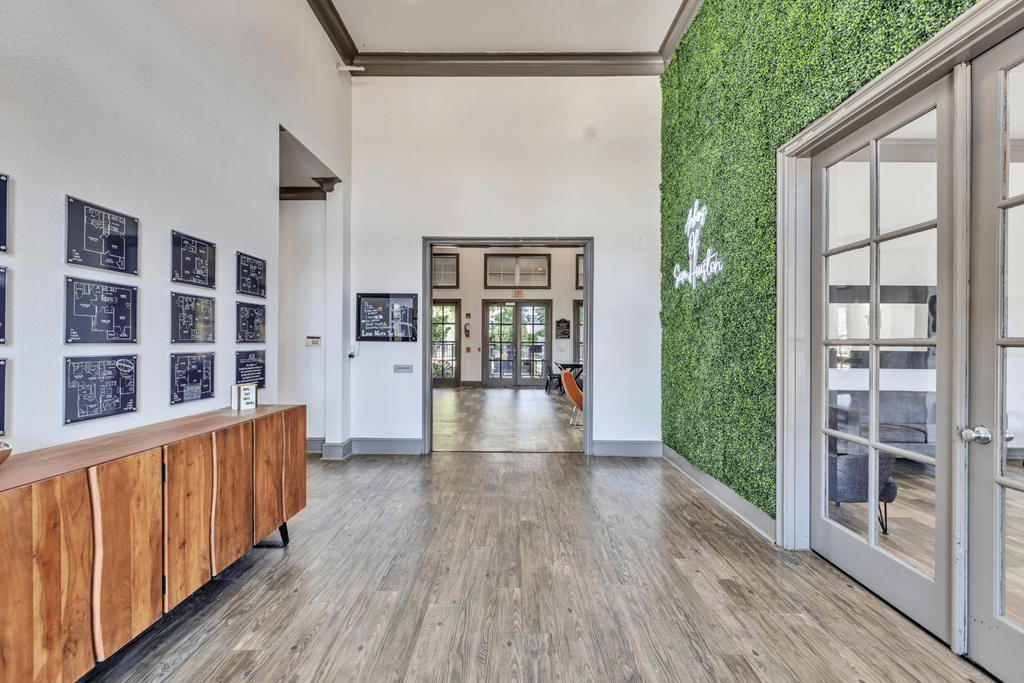 a hallway with large glass doors and a green wall on the side of a building