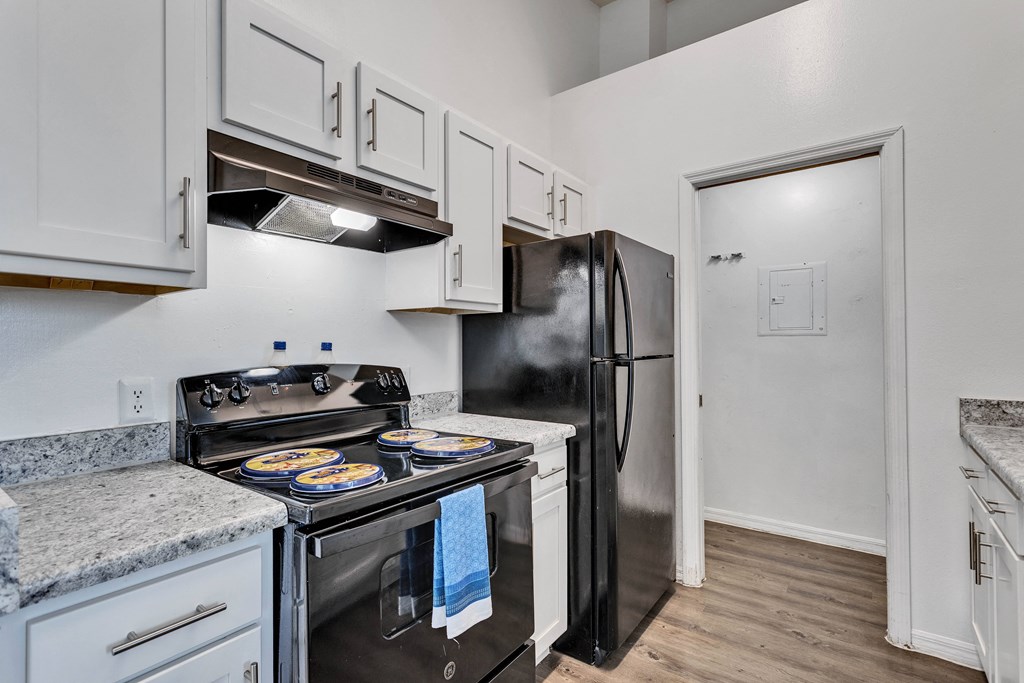 a kitchen with white cabinets and stainless steel appliances and a black refrigerator