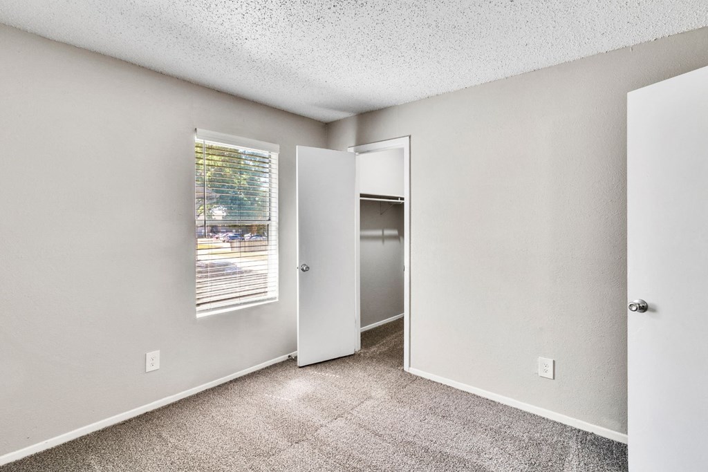 an empty room with a window and a door to a closet