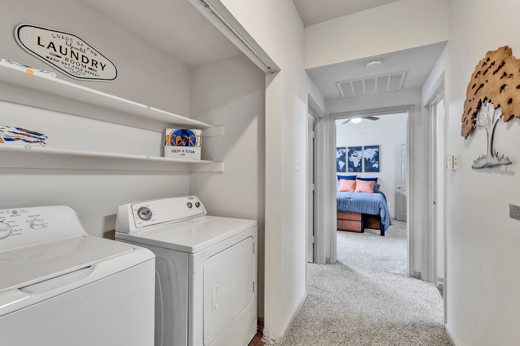 a laundry room with a washer and dryer and a bedroom with a bed