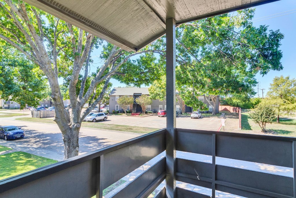 a balcony with a view of a street and trees