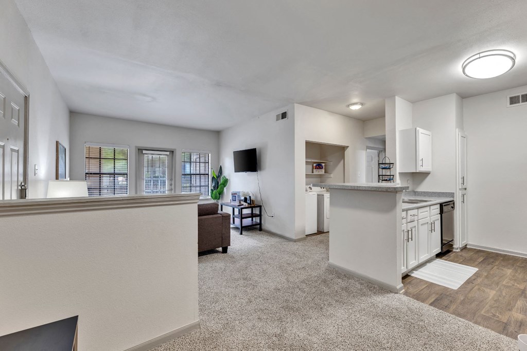 the living room and kitchen of an apartment with a view of the dining room and