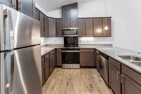 A kitchen with a stainless steel refrigerator and wooden floors.