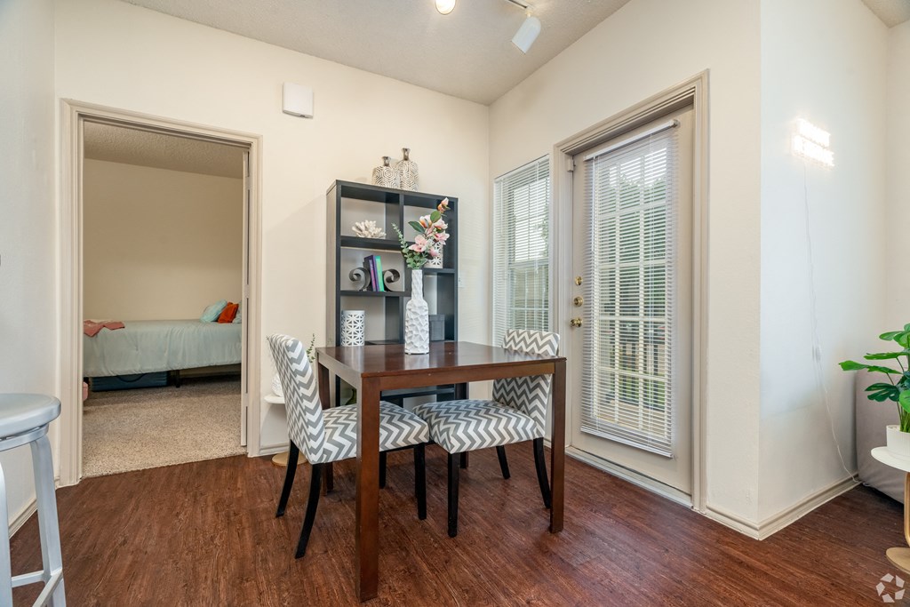 a dining room with a table and chairs and two windows