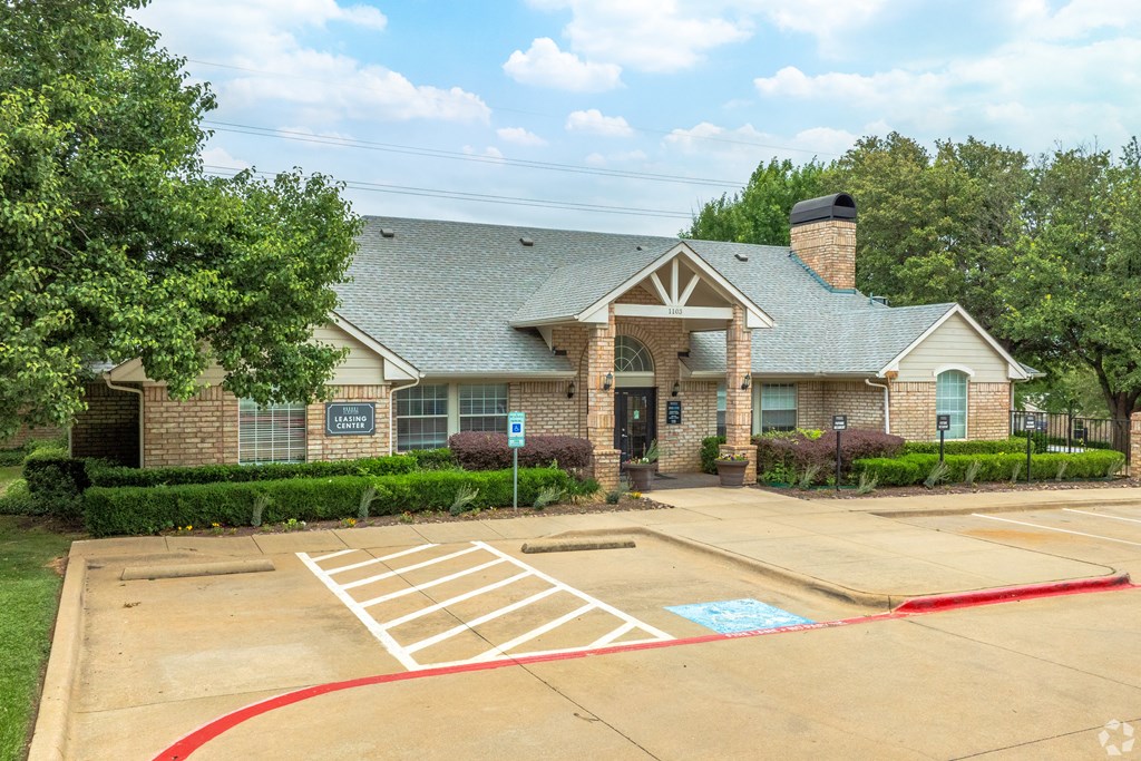 the front of a brick house with a driveway and a parking lot