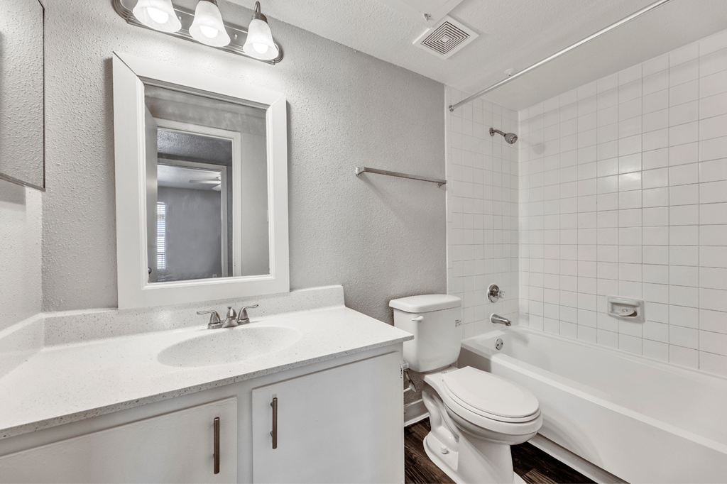A white bathroom with a toilet, sink, and mirror.