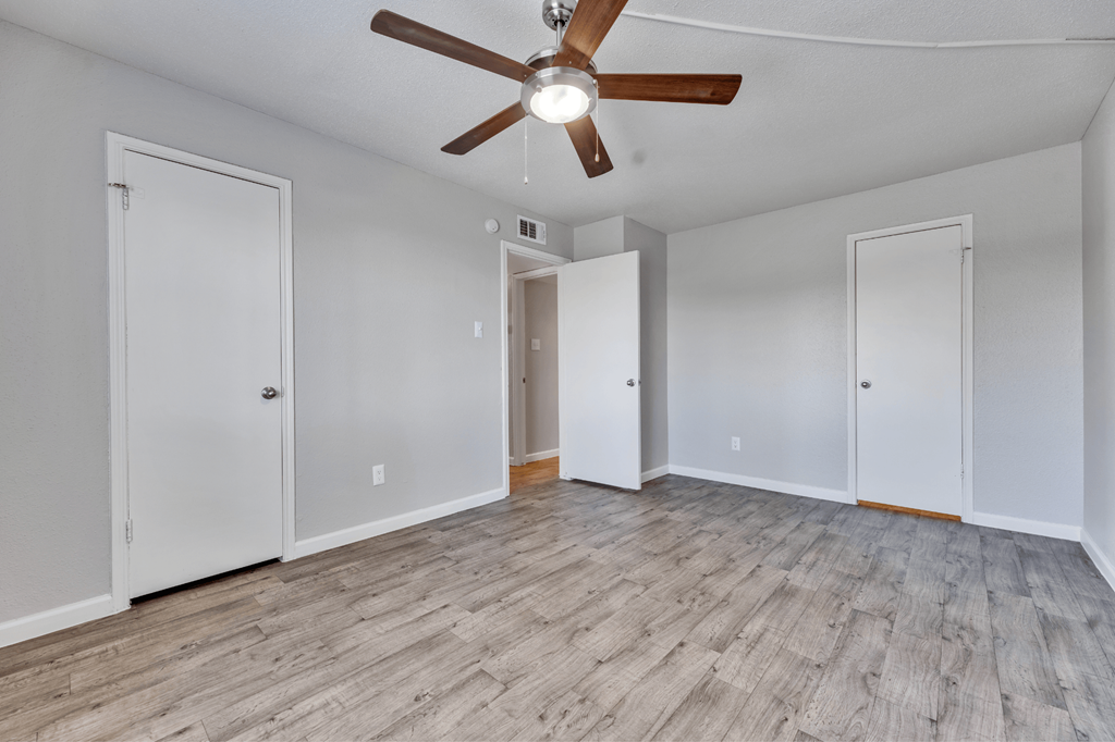 A room with a ceiling fan and wooden flooring.