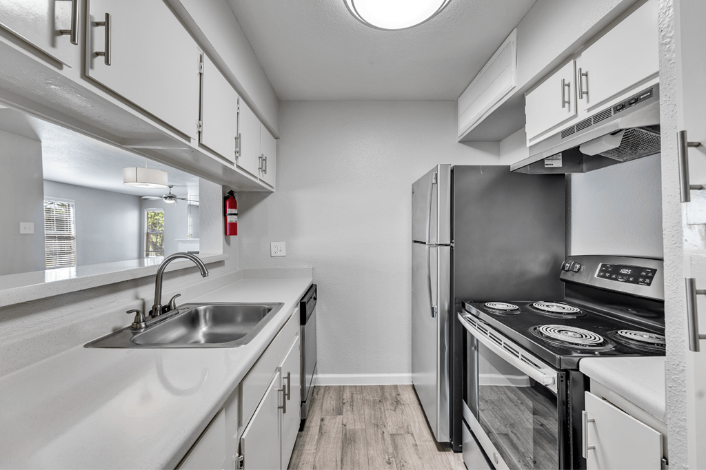 A modern kitchen with a stainless steel refrigerator and a black stove top.
