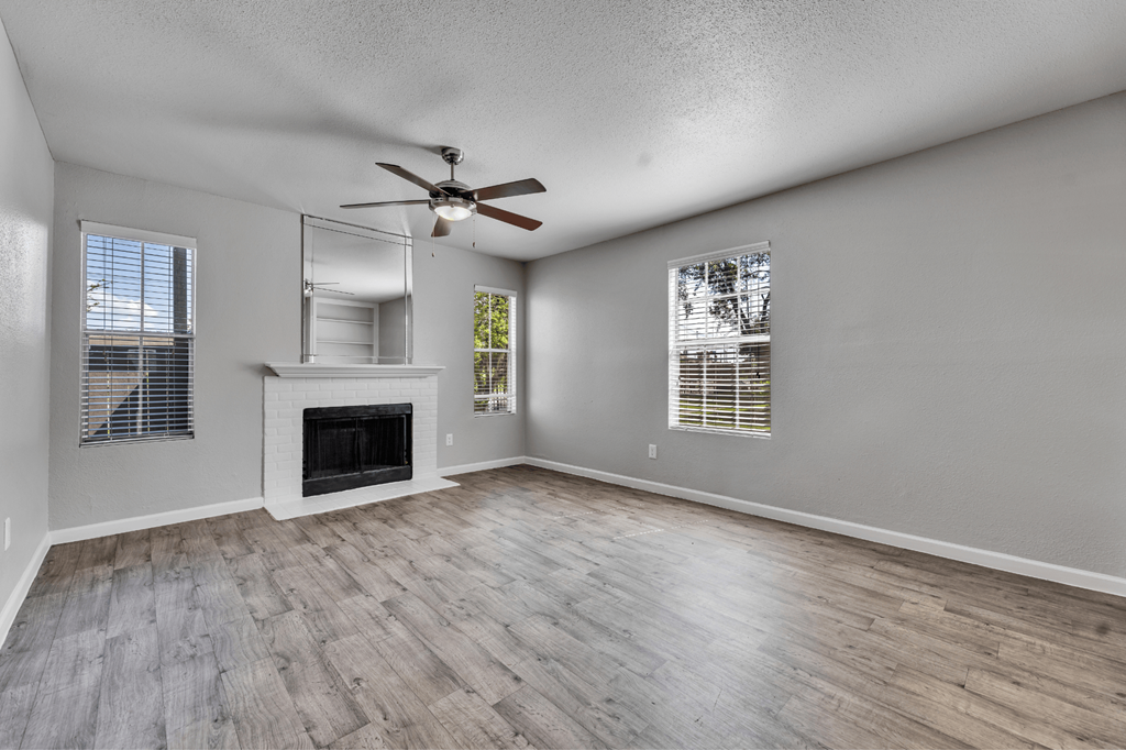 A spacious room with a fireplace, a ceiling fan, and a large mirror.