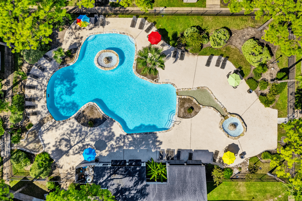 An aerial view of a swimming pool surrounded by trees and a playground.