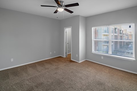 A room with a ceiling fan and a window overlooking a cityscape.