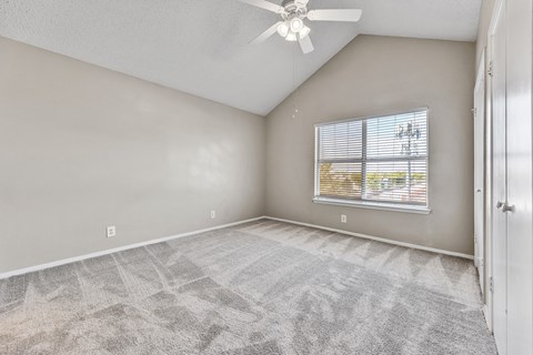 A room with a ceiling fan and a window with blinds.