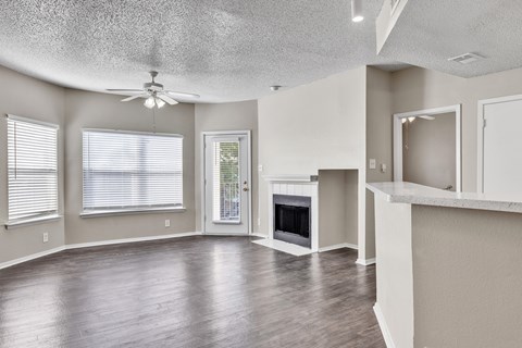 A spacious living room with wood flooring and a fireplace.