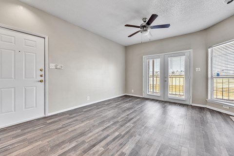 A room with a white door, a ceiling fan, and a window with blinds.