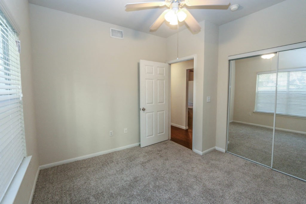 a bedroom with a ceiling fan and a mirror