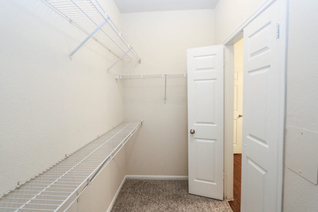 a walk in closet with white closet doors and a white door to a closet