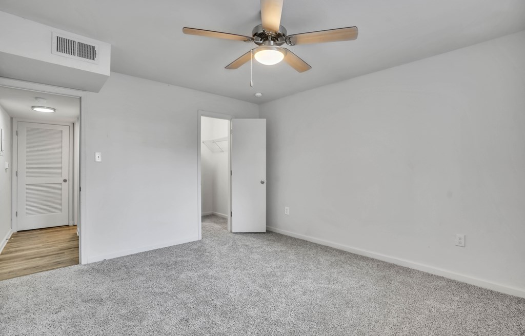 an empty living room with a ceiling fan and white walls