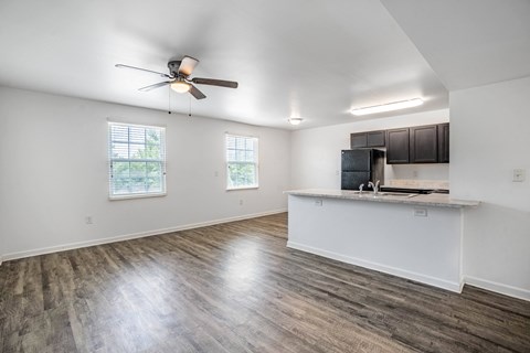 A spacious room with a ceiling fan and wooden flooring.