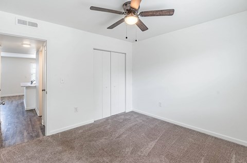 an empty living room with white walls and a ceiling fan