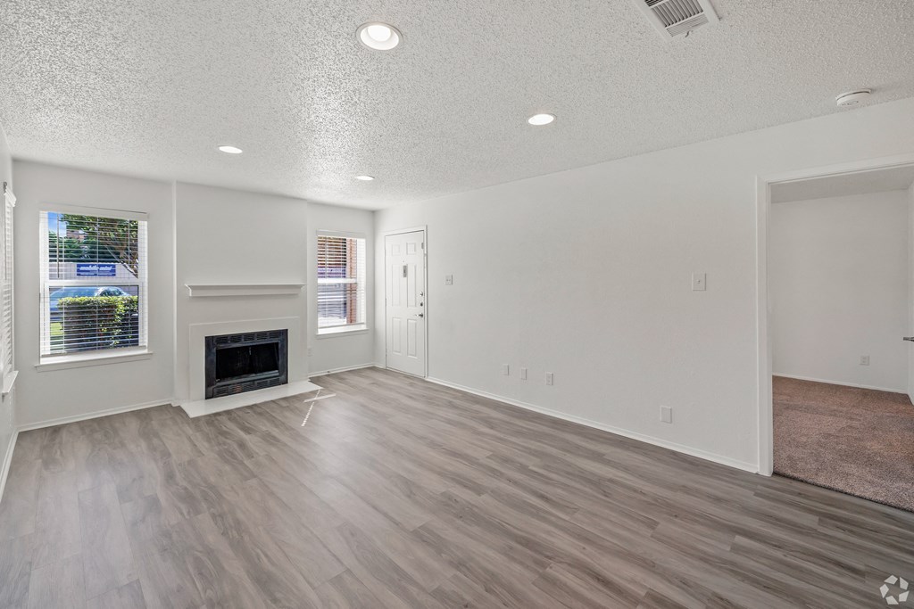 an empty living room with a fireplace and wooden floors