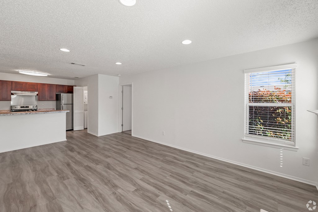 an empty living room and kitchen with a large window