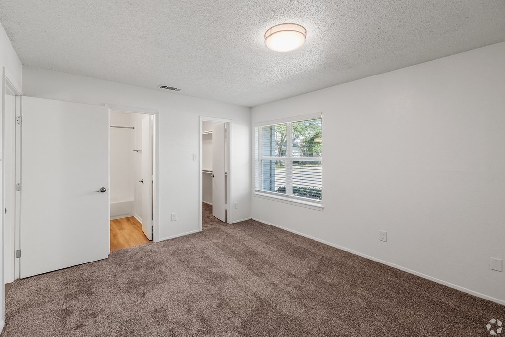 an empty living room with carpet and a window