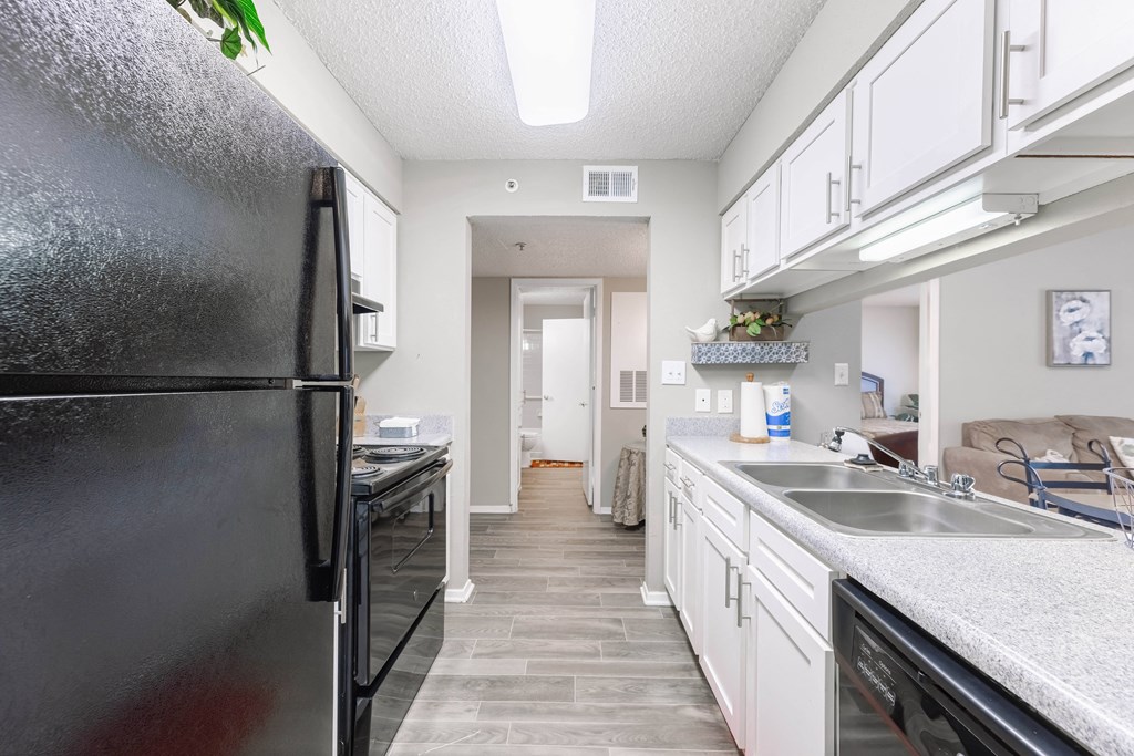 a kitchen with white cabinets and stainless steel appliances and a black refrigerator
