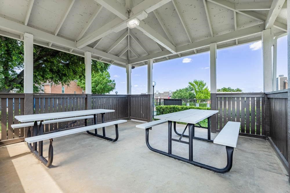 a covered patio with picnic tables and benches