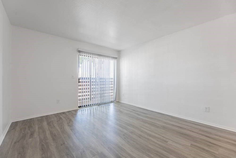 an empty living room with wood flooring and a window