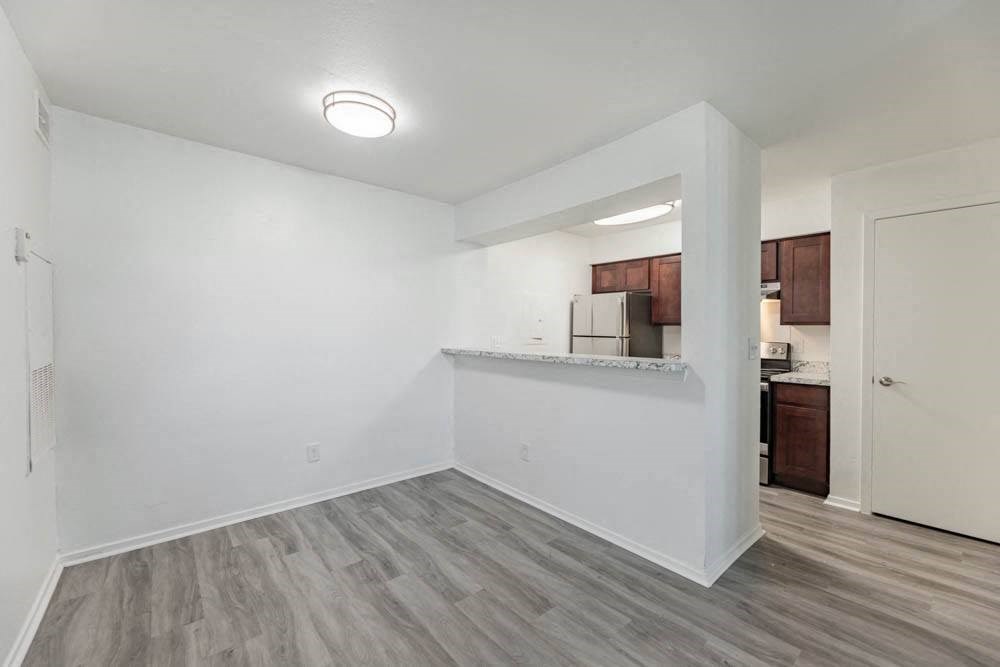 an empty living room with a kitchen in the corner