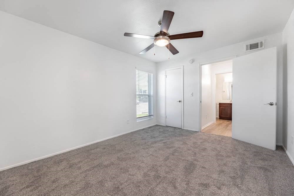 an empty living room with a ceiling fan