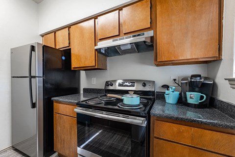 a kitchen with a stove and refrigerator and wooden cabinets