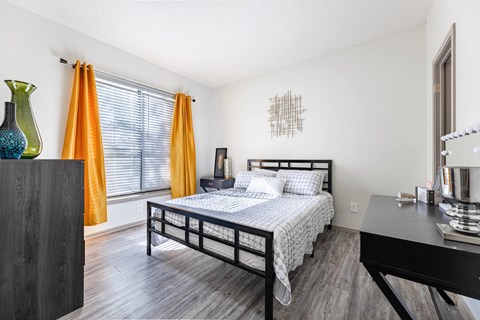 a bedroom with a bed and a window with orange curtains