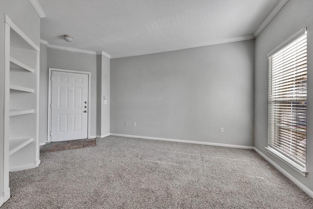 an empty living room with a white door and a window