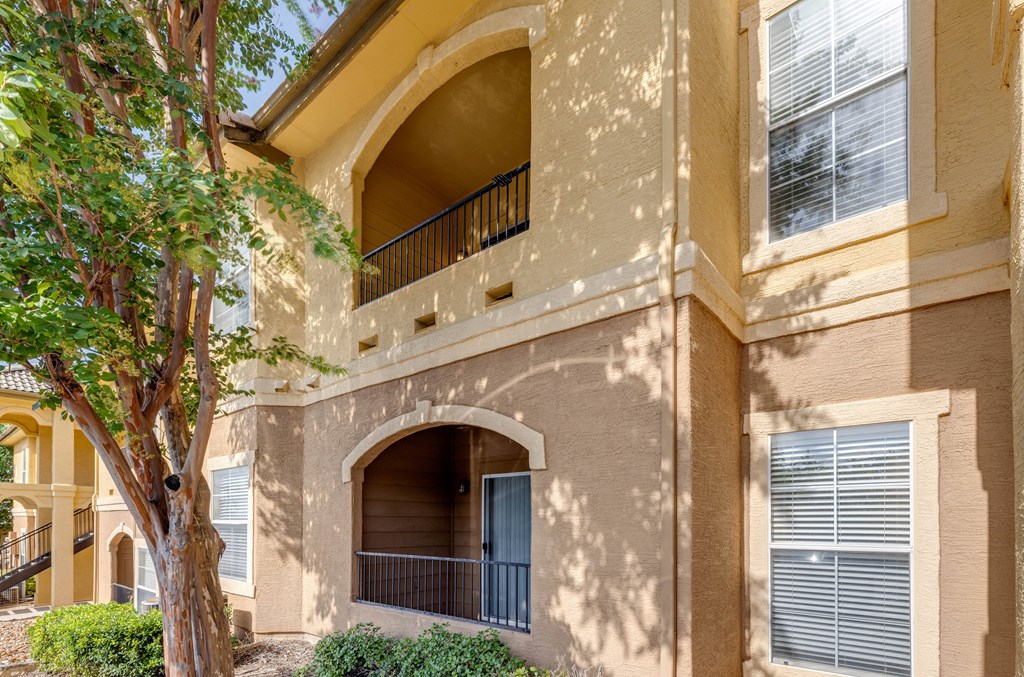 a building with a balcony and a tree in front of it