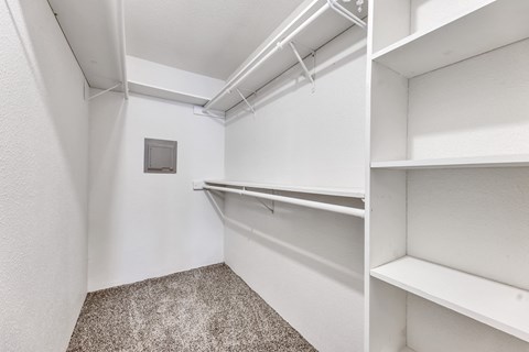 A white closet with shelves and a carpeted floor at Arrowood Apartments, Houston, TX