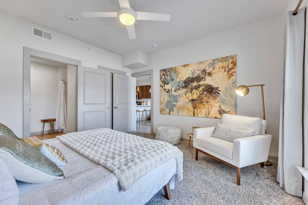 a bedroom with a bed and a chair and a ceiling fan