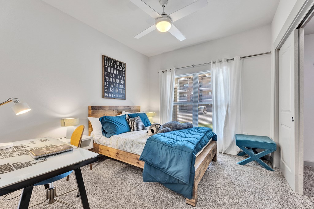 a bedroom with a bed and a desk and a ceiling fan