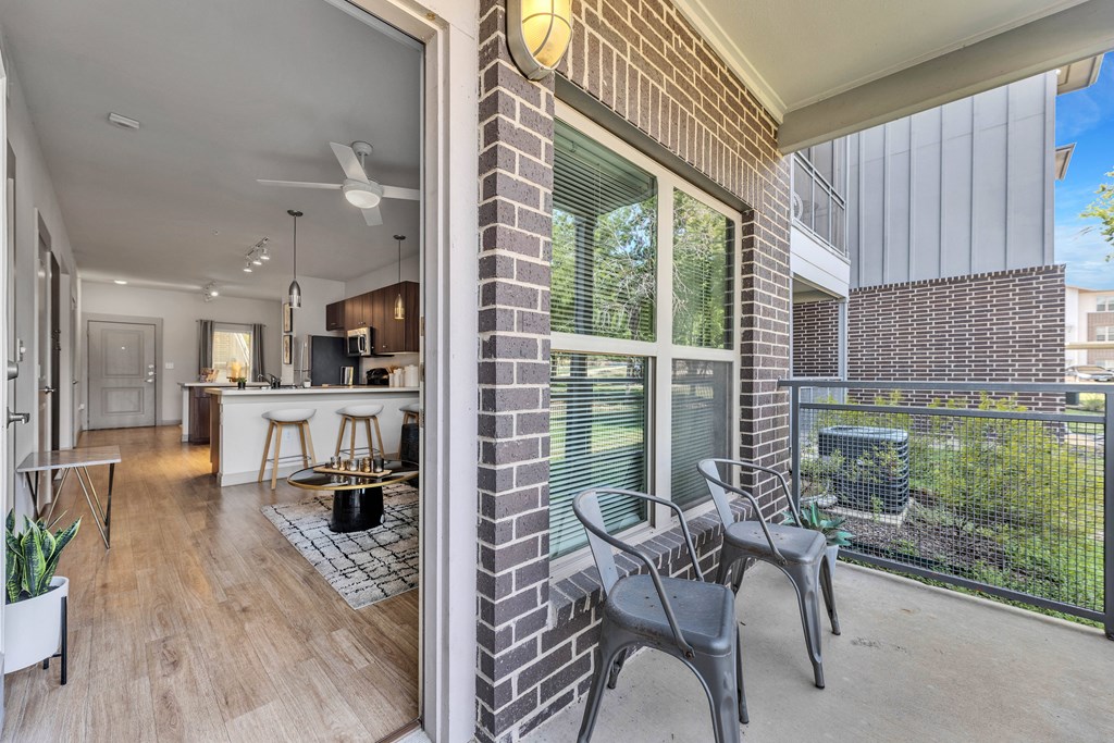 a balcony with a table and chairs and a kitchen in the background