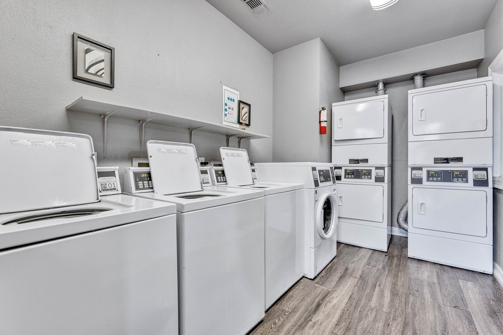 the laundry room has many washes and dryers and a row of washing machines