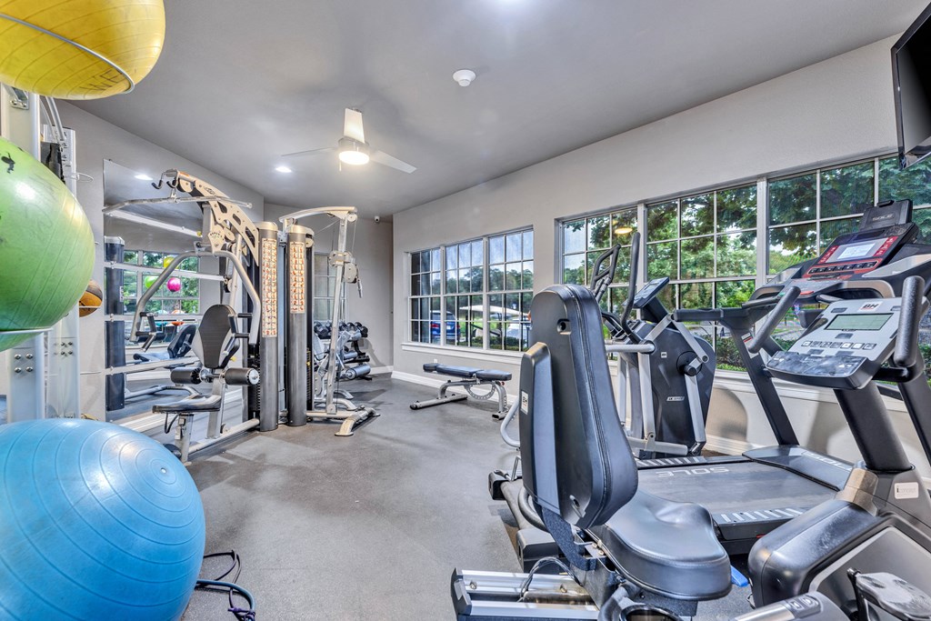 gym with cardio equipment and windows at the district flats apartments in lenexa