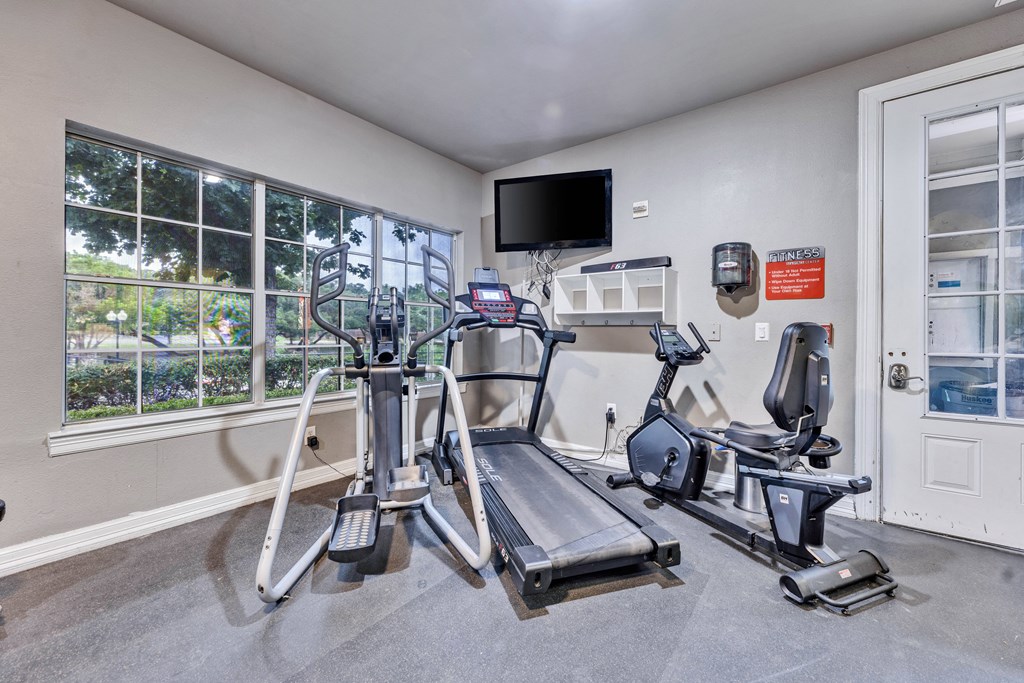 a gym with exercise equipment and a tv on the wall