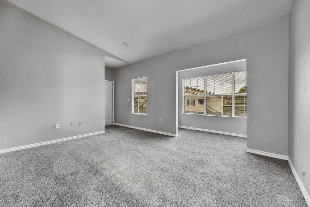 the living room of a new home with carpet and a large window
