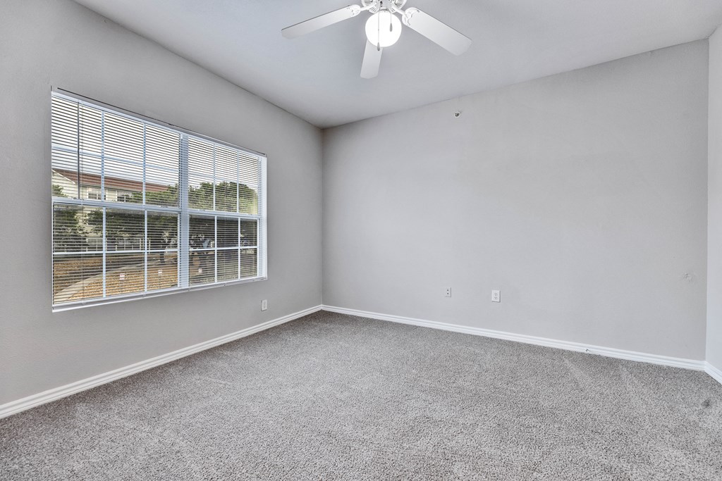an empty room with a window and a ceiling fan