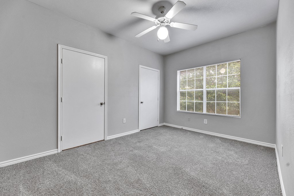 an empty room with a ceiling fan and a window