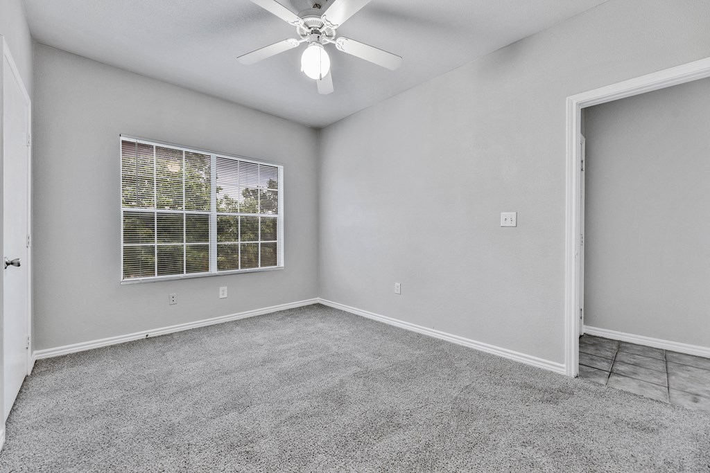 an empty room with a window and a ceiling fan