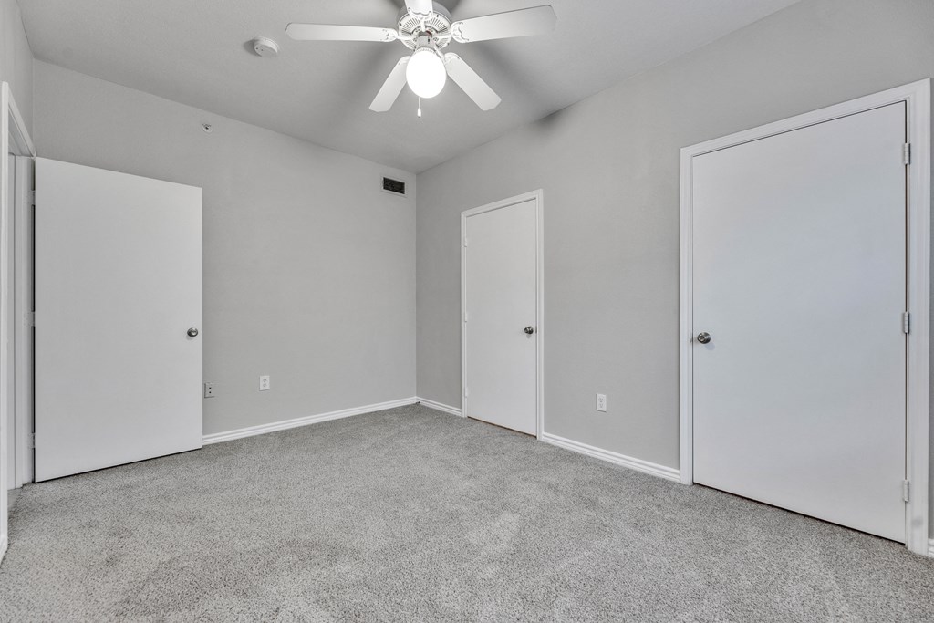 an empty room with two doors and a ceiling fan