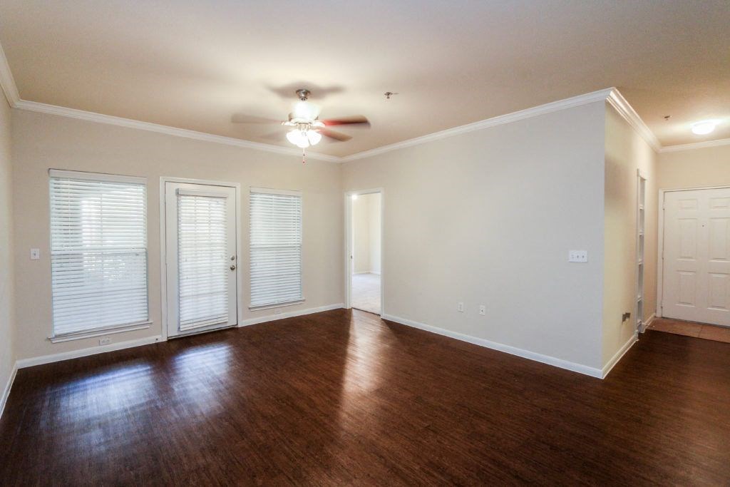 an empty living room with wood floors and a ceiling fan