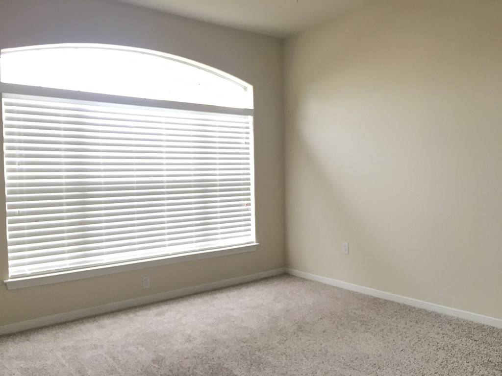 an empty room with a large window with blinds
