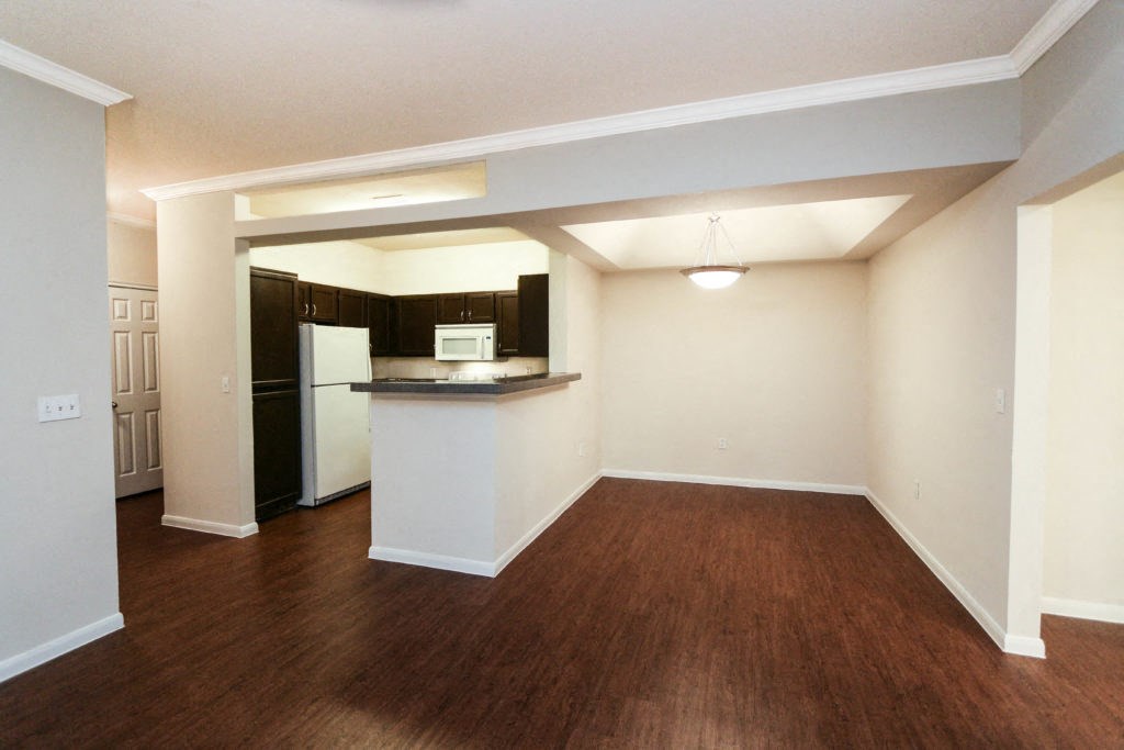 an empty living room and kitchen with a wood floor